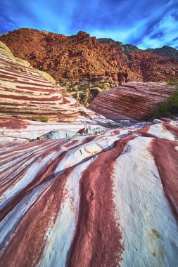 Las Vegas Nevada yakınlarındaki Red Rock Kanyonu 'nda kayaların üzerinden renkli kumtaşı katmanları akıyor. Koyu kırmızı çizgiler ve engebeli oluşumlar göz kamaştırıcı bir çöl manzarası yaratır..
