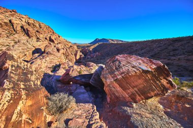 Çarpıcı kırmızı kumtaşı kayaları ve katmanlı kanyon duvarları Las Vegas Nevada yakınlarındaki Red Rock Kanyonu 'nda canlı mavi bir gökyüzünün altında güneşleniyor. Bu ikonik çöl manzarası, saf güzelliği ve ruhun