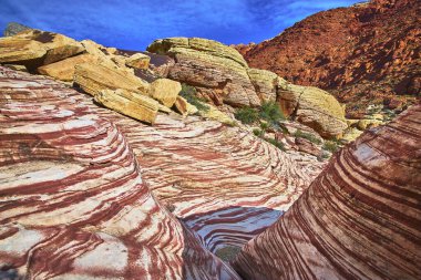 Belirgin katmanlı kumtaşı ve kalın kaya oluşumları Las Vegas Nevada yakınlarındaki Red Rock Kanyonu 'nu tanımlıyor. Yoğun mavi gökyüzü ve engebeli arazi Ash Spring ve Kraft 'ın ruhunu yakalar.