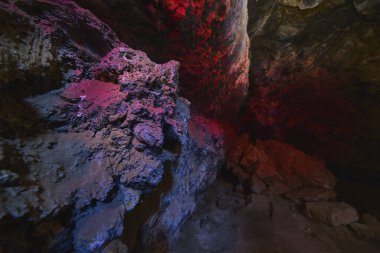 Canlı ışık resmi, Kelso California yakınlarındaki bir Mojave lav tüpünün içindeki volkanik kayayı aydınlatıyor. Dramatik renkler ve sert dokular bu yeraltı sahnesinde macera ve jeolojik harikayı çağrıştırıyor..