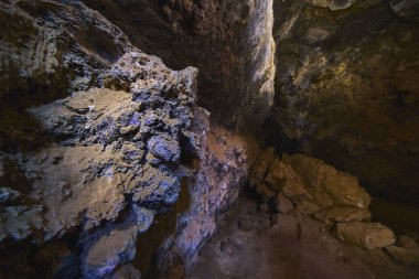 Volkanik kaya oluşumları ve desenli mağara duvarları Kelso California 'daki Mojave Çölü lav tüpünü dramatik bir ışıkla dolduruyor. Engebeli kayalar ve doğal taş yüzeyler macera hissi yaratıyor.