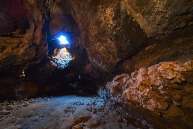 Güneş ışığı, Kelso California yakınlarındaki Mojave 'de bulunan bir lav tünelinde doğal bir çatı penceresinden akar. Engebeli volkanik kaya duvarları ve mağara tabanı dramatik ve gizemli bir yeraltı manzarası yaratır..