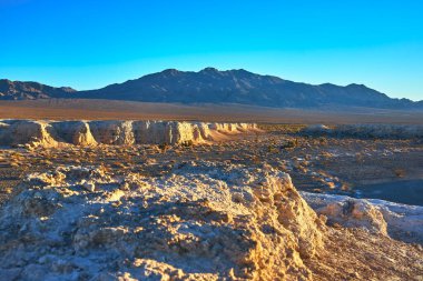 Sıcak güneş ışığı, Las Vegas yakınlarındaki Tule Springs Fosil Yatağı 'nın engebeli kayalıklarını ve çöl manzarasını vurguluyor..