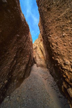 Ürkütücü Kanyon Arizona 'da, parlak mavi gökyüzünün altında, sarmal bir çakıl yolu örten yüksek kaya duvarlar. Dramatik slot kanyonu macera hissi yaratır ve eşsiz çöl jeolojisini ön plana çıkarır..