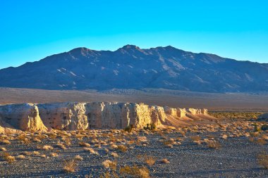 Altın saat ışığı, Las Vegas Nevada yakınlarındaki Tule Springs Fosil Yatağı 'nın engebeli uçurumlarını ve kurak çöl tabanını aydınlatmakta..