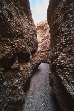 Arizona slot kanyonunda sarmal bir çakıl yolunun her iki tarafında uzun kaya duvarlar belirgin bir şekilde yükselir. Güneş ışığı Ürkütücü Kanyon 'un dokusunu ve derinliğini vurguluyor. Maceracı bir hava yaratıyor.