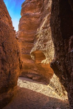 Güneş ışığı, Arizona 'daki Ürkütücü Kanyon' un yontulmuş duvarlarını ve kumlu zeminini aydınlatıyor. Yuvarlak kanyon ve desenli kaya dramatik ve maceralı bir çöl sahnesi yaratır..