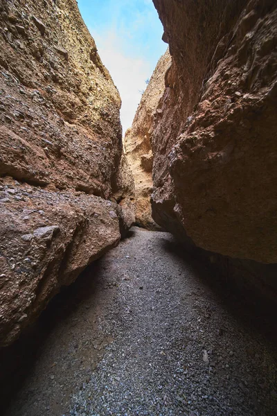 Arizona 'da Spooky Canyon' daki çakıllı bir yolun üzerinde yükselen kumtaşı duvarlar. Parlak mavi gökyüzü, Amerika 'da macera ve gizem hissi yaratan dar kanyondan bakıyor.