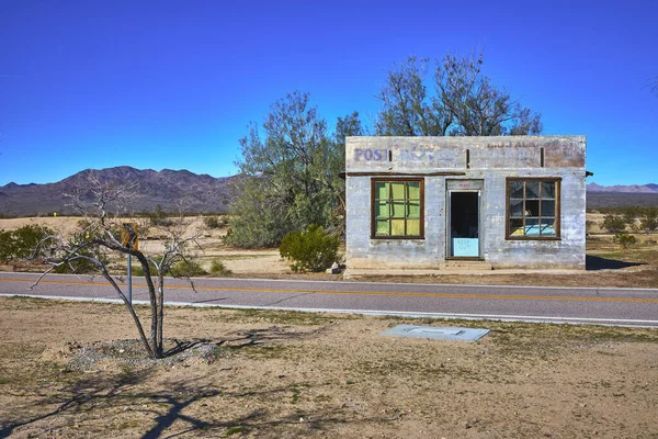 Kelso California 'daki Mojave Çölü' nde terk edilmiş bir postane duruyor. Güneş ışığı boş hayalet kasabayı ve kuru manzarayı vurguluyor. İzolasyon ve tarih hissi uyandırıyor..