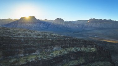 Las Vegas Nevada yakınlarındaki Kovboy Kanyonu 'nun havadan görünüşü altın güneş ışığı engebeli Kızıl Kaya Kanyonu dağlarını ve geniş çöl manzarasını aydınlatıyor. Sahne sonsuzluğu yakalar ve...