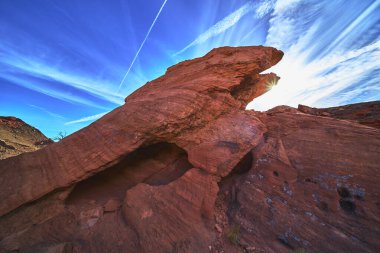 Las Vegas Nevada yakınlarındaki Ateş Kasesi 'nde çarpıcı bir kırmızı kumtaşı oluşumunun arkasında güneş ışığı parlıyor. Canlı mavi gökyüzü ve engebeli kaya dokuları Amerika 'da enerji dolu bir açık hava sahnesi yaratıyor..