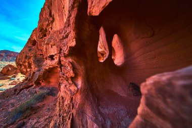Canlı kırmızı kumtaşı kemerleri ve sert dokular Las Vegas Nevada yakınlarındaki Ateş Kasesi 'ni tanımlıyor. Güneş ışığı doğal kaya boşluklarından akar dramatik jeoloji ve canlı çöl renklerine vurgu yapar..