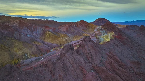 Las Vegas Nevada yakınlarındaki dramatik Lava Butte manzarası renkli çöl dağları ve canlı bir akşam gökyüzünün altında dolambaçlı bir yol. Engebeli arazi ve geniş ufuklar keşfi çağrıştırıyor.
