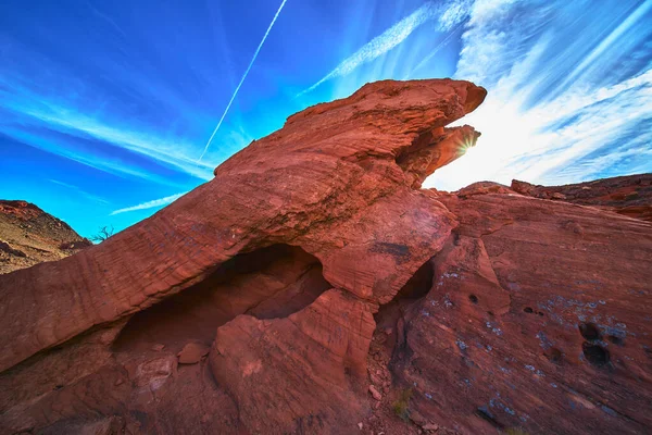 Las Vegas Nevada yakınlarındaki Ateş Kasesi 'nde çarpıcı bir kırmızı kumtaşı oluşumunun arkasında güneş ışığı parlıyor. Canlı mavi gökyüzü ve engebeli kaya dokuları Amerika 'da enerji dolu bir açık hava sahnesi yaratıyor..