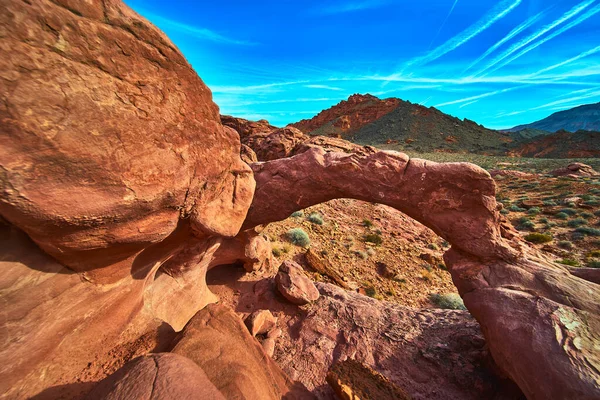 Las Vegas Nevada yakınlarındaki Ateş Kasesi 'nin kırmızı kayalarından dramatik bir kumtaşı kemeri yükseliyor. Canlı renkler ve berrak gökyüzü bu birleşik çöl manzarasının ve doğal güzelliğin altını çiziyor.