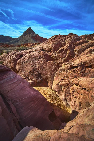 Güneş ışığı, Nevada, Las Vegas yakınlarındaki çarpıcı kızıl kaya oluşumlarını ve engebeli dağları aydınlatır. Ateş Kasesi parlak mavi bir gökyüzünün altında sergileniyor dramatik bir çöl yaratıyor.