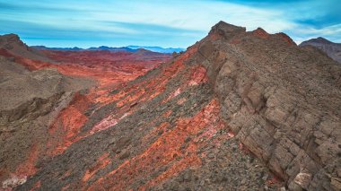 Dramatik kızıl kaya oluşumları ve Overton Nevada yakınlarındaki engebeli çöl sırtı. Uzak dağ sıraları ve Birleşik Devletler 'in güneybatısının muazzam güzelliğini yansıtan canlı bir gökyüzü..