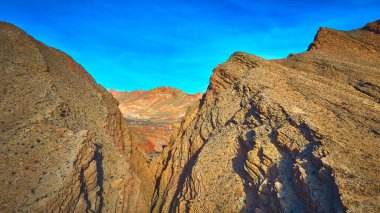 Overton Nevada yakınlarındaki dramatik kaya kayalıklarının ve kanyon oluşumlarının canlı mavi gökyüzünün altında havadan görünüşü. Yıldönümü Dar bölgesinde engebeli dokular ve renkli çöl dağları var.