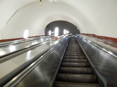 Moskova metrosunun yürüyen merdivenleri dikey lambalarla aydınlanıyor.