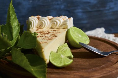 Bir dilim limonlu turta. Yanında limon var. Tahtanın üstünde..