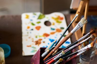 Sanat atölyesinde fırçalı ve tuvalli bir masa. Arkaplan.