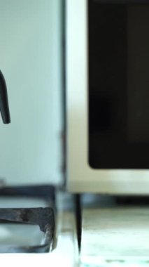 Gayzer kahve makinesi / moka demliği, yanan bir ocağın üzerinde duruyor, kamera sağdan sola hareket ediyor, yakın çekim, dikey video, ses yok, Full HD.