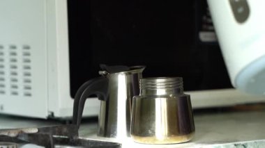 Elektrikli çaydanlıktan gelen su bir moka demliğini, bir gayzer kahve makinesini, yakın çekim, tam HD doldurur..