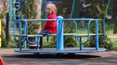 Ukrayna, Kyiv - 24 Nisan 2019. 6 yaşında bir kız çocuk parkında tek başına atlıkarıncaya biniyor. tam Hd.