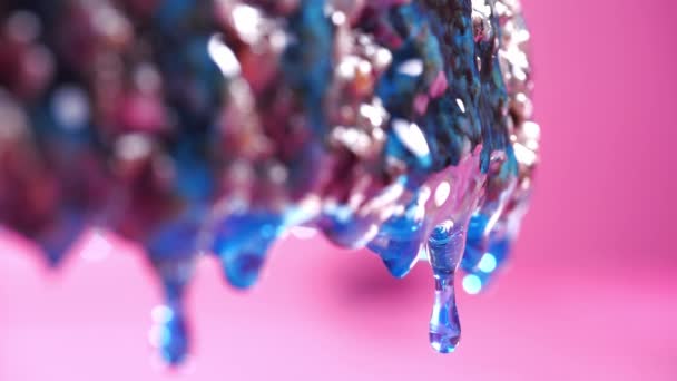 濃い基部からゆっくりと青いエポキシ滴の滴 ピンクの背景 クローズアップ — ストック動画
