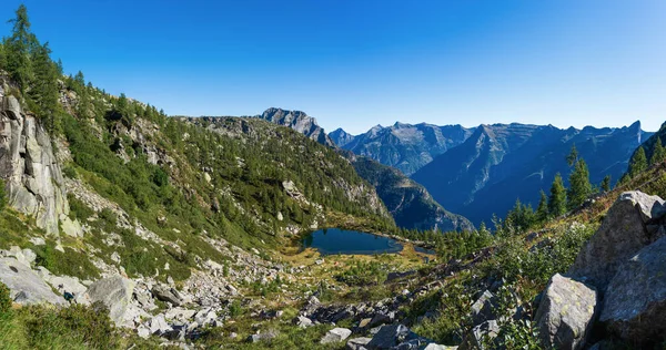 A red tent at a small lake in the mountains of Ticino on a summers mornig.