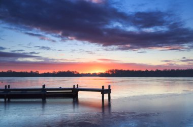 Bir kış günü iskelede dramatik ve renkli bir gün doğumu..