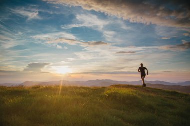 Güzel bir günbatımında dağlarda koşan bir atlet. Hareket bulanıklığı ve eski film efektiyle.