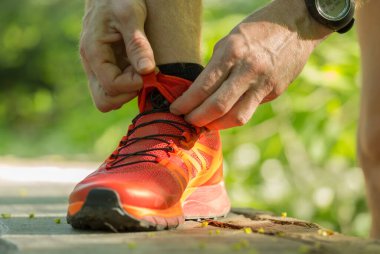 Koşucu çimenlerdeki koşu ayakkabılarının bağcıklarını düzeltiyor. Sığ Savunma Bakanlığı..