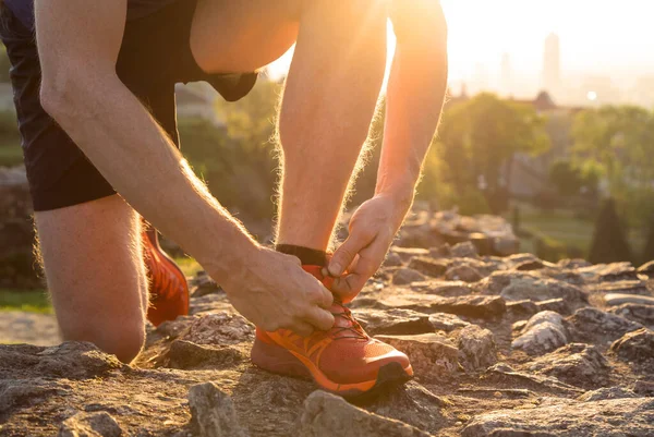 Şehir parkında spor ayakkabısının bağcıklarını düzelten bir sporcu. Kentsel spor konsepti.