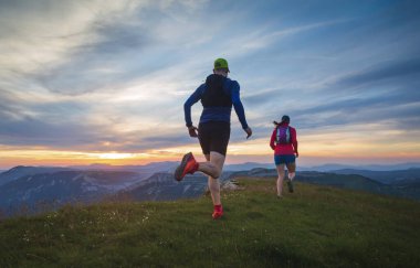 Gün batımında tepelerde koşan iki sporcu. Sığ Savunma Bakanlığı..