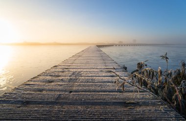 Roegwold 'un soğuk ve sonbahar gündoğumunda doğada bir iskeledeki (Knuppelpad) stoklama. Sığ Savunma Bakanlığı..