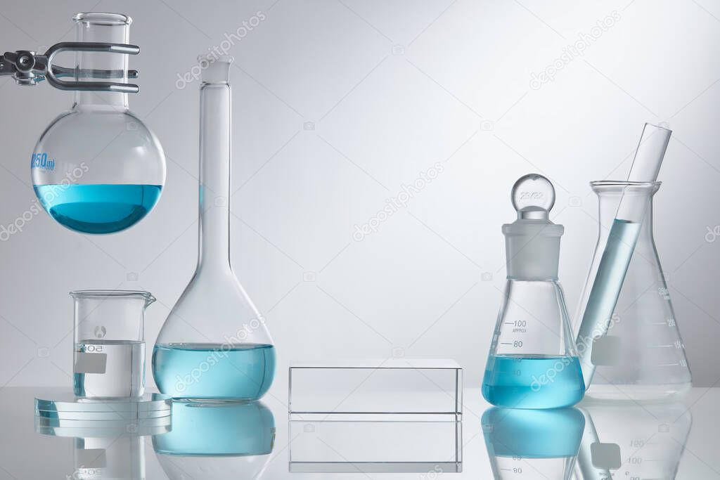 Stage showcase cosmetics on glass pedestal modern in laboratory equipment. Laboratory glass equipment with blue water ingredients on white background. Research and development cosmetics concept