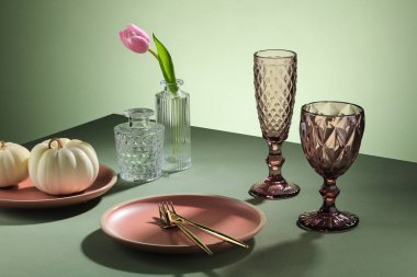 Pastel renklerde yemek masası, çiçekler, cam şarap, akşam yemeği tabağı, düğün resepsiyonu ya da yeşil arka plan ve ışık duvarındaki diğer şenlikli etkinlikler için. Dekorasyon sanatı