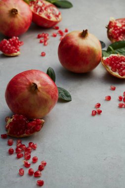 Olgun lezzetli kırmızı nar meyvesi, gri beton arka planda pastel bir tepside yapraklarla. en üstteki görünüm