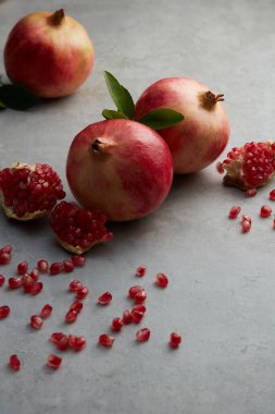 Taze olgun nar, açık nar ve yaprakları gri beton arka planda olan tohumlar. seçici odak.