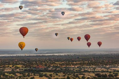 Gün doğumunda Myanmar 'daki Pagan tapınağının üzerinde birçok sıcak hava balonu yükselir.