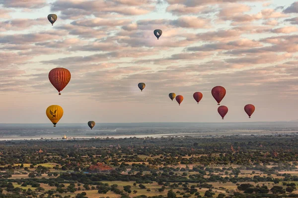 Gün doğumunda Myanmar 'daki Pagan tapınağının üzerinde birçok sıcak hava balonu yükselir.