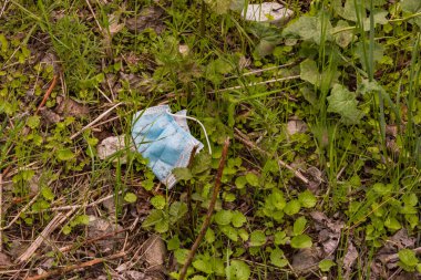 Kullanılmış bir cerrahi maske toprak bir yolda kayboldu ve çevreyi kirletti.