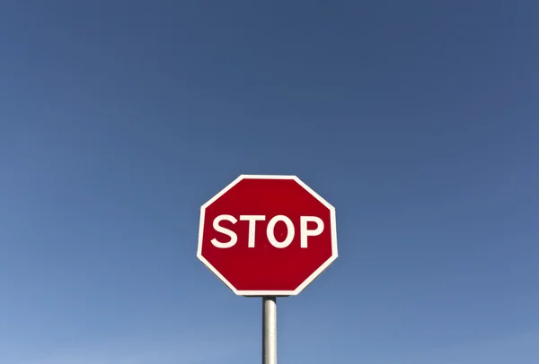 Czerwony znak stop i błękitne niebo. — Zdjęcie stockowe