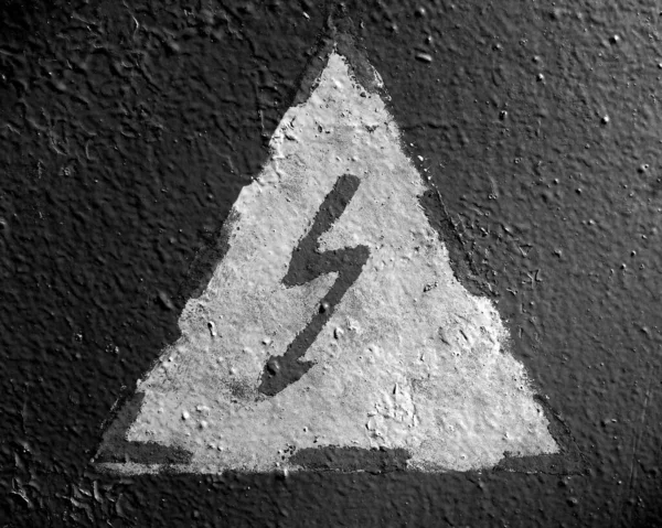 Hand painted electricity hazard sign on grungy surface. Signs and symbols background