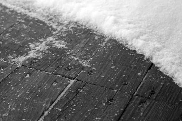 Snow on old wooden terrace floor. Seasonal background and view.