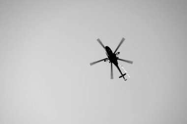 Helicopter flying in clear sky in black and whte. Conceptual background.