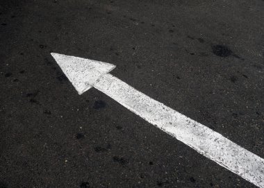 Solu işaret eden asfaltta beyaz ok. Fikirlerin kavramları ve işaretleri.