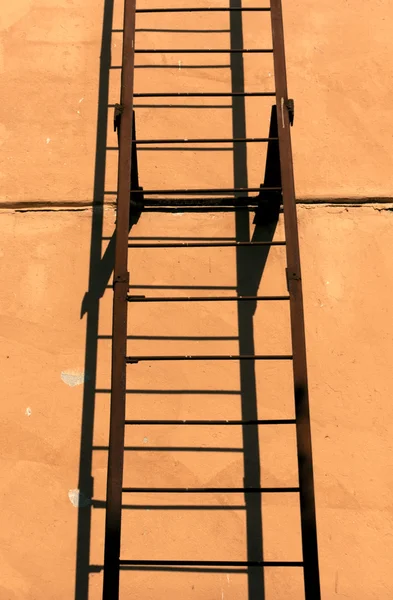 Old metal ladder and orange wall. — Stock Photo, Image