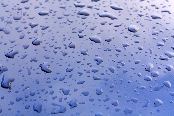 Regnet droppar på mörk blå metall yta. — Stockfoto